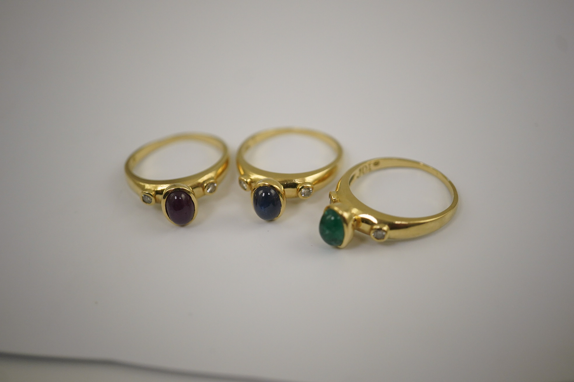 A suite of three modern 18k gold and gem set rings